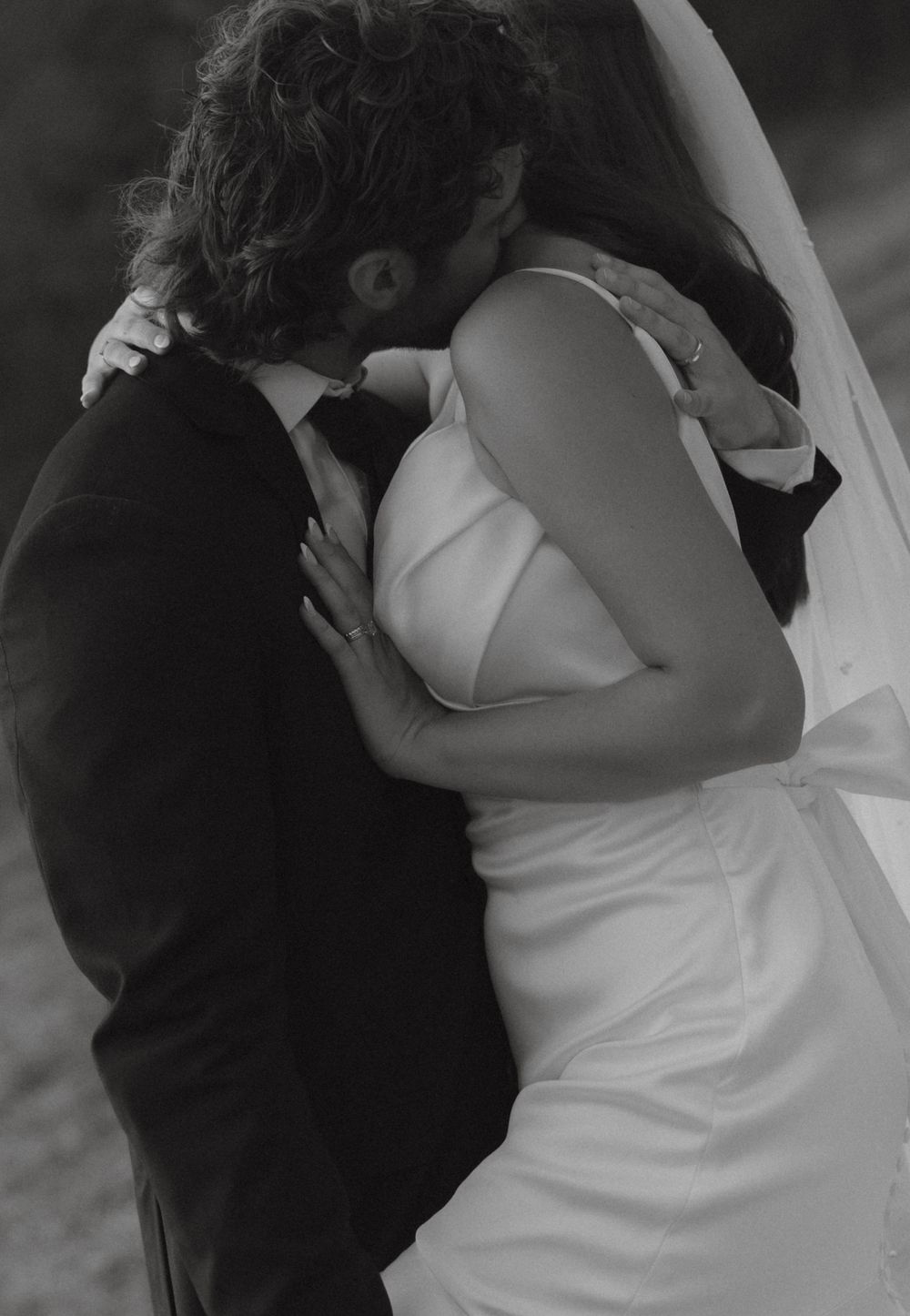 Black and white photo of bride and groom sharing a passionate kiss on their wedding day.