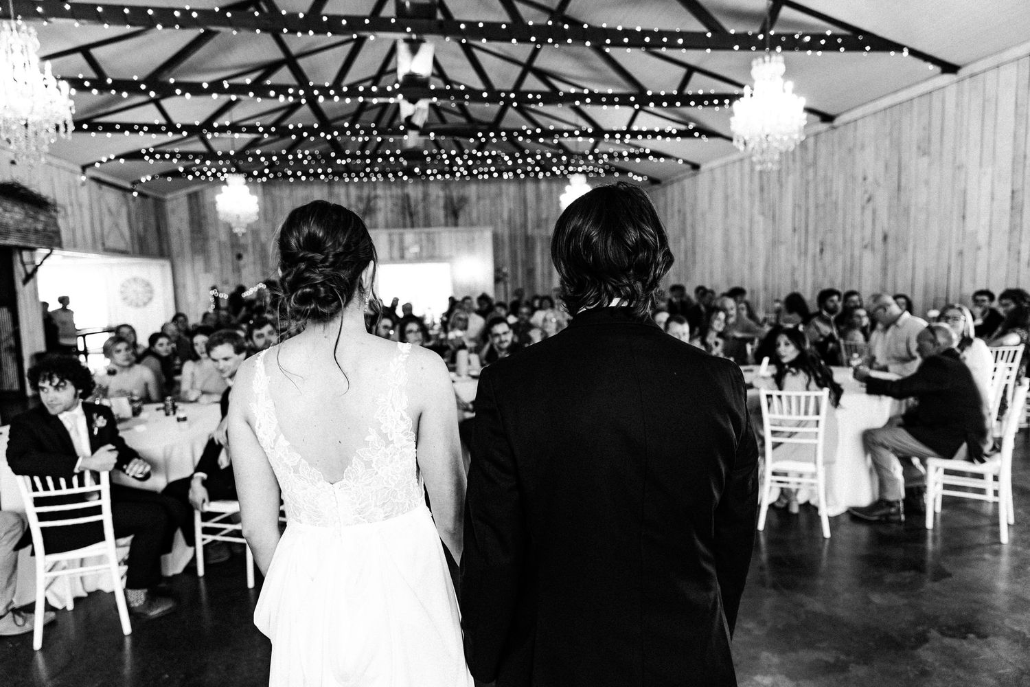 Elegant wedding reception venue with chandeliers and white chairs decorated for a celebration.