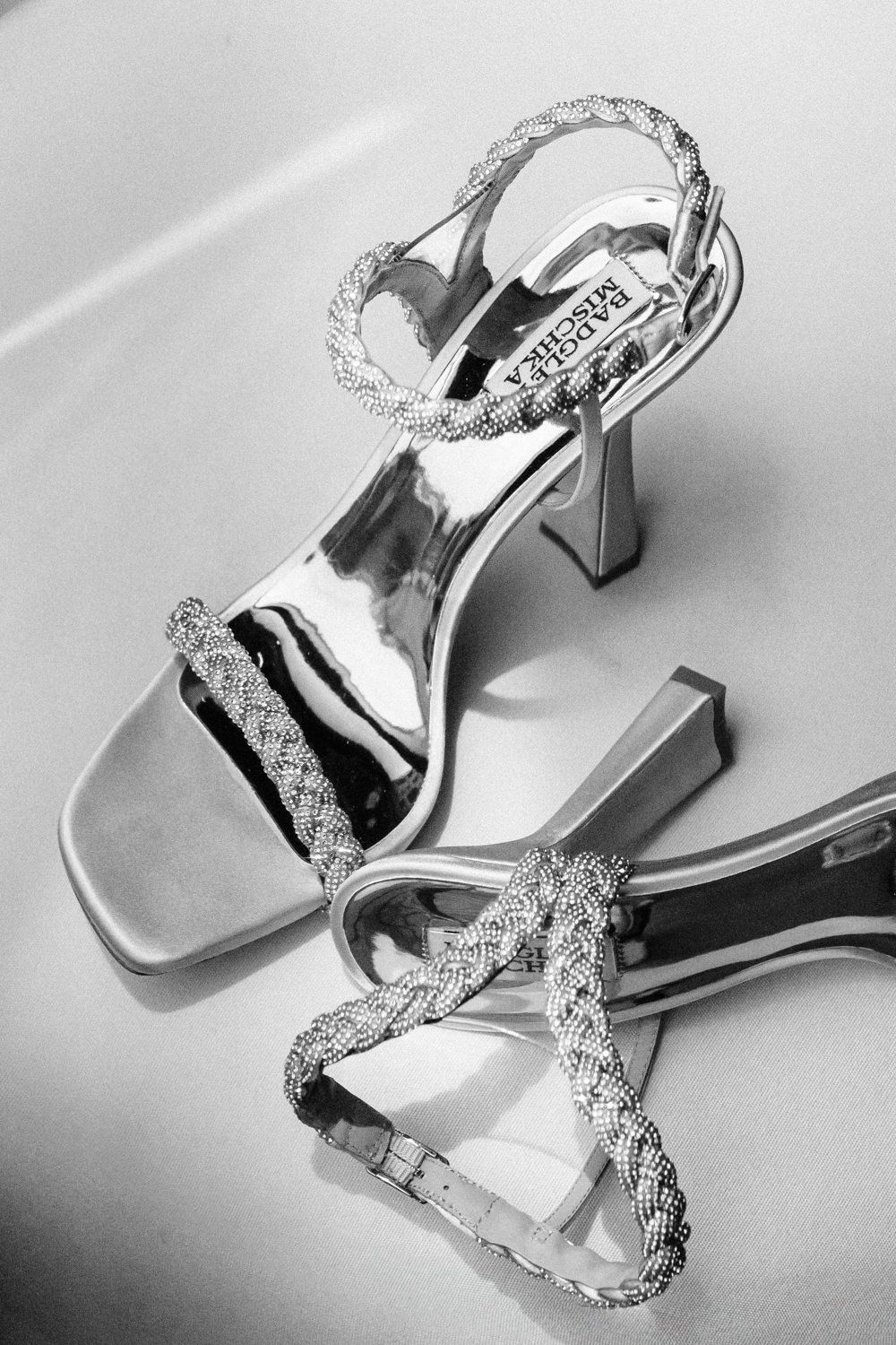 Silver metallic wedding sandals with crystal straps photographed in black and white.