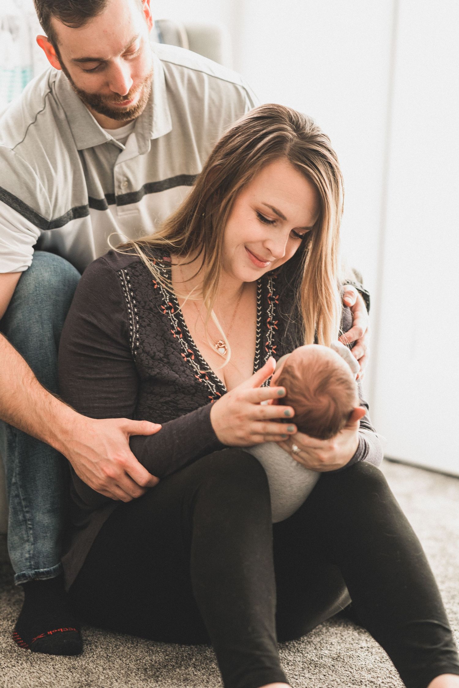 Mother gently brushing newborns hair while father looks on