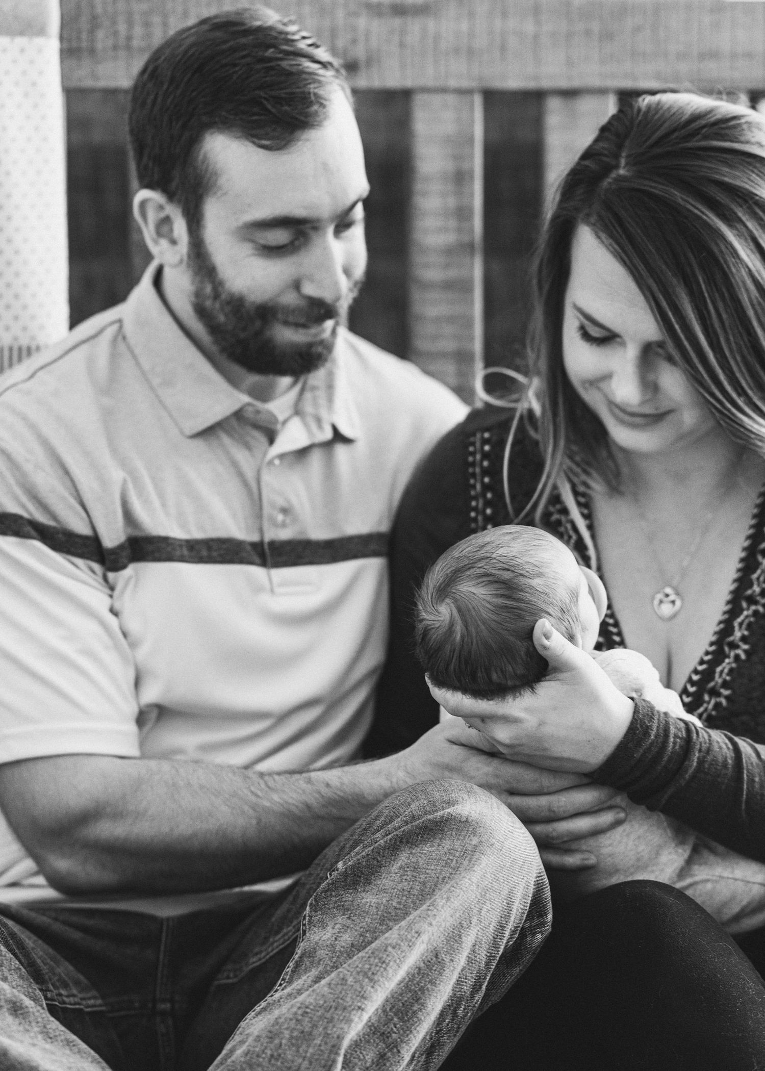 Black and white image of new parents holding baby in the nursery