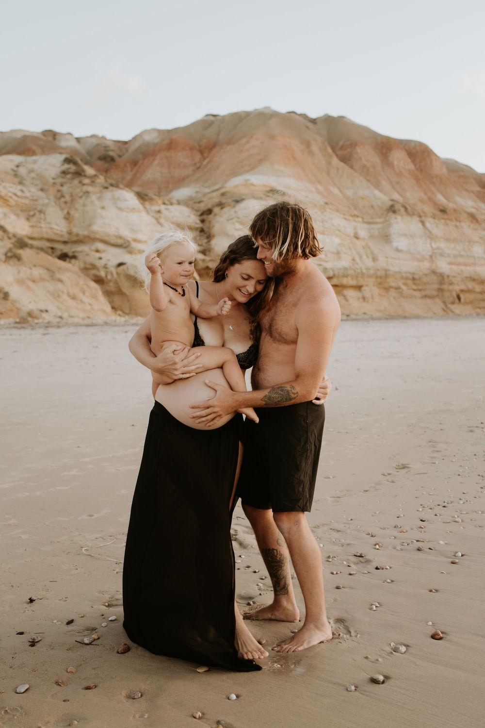 Young family during a natural sunset pregnancy photography session at Maslin Beach, South Australia