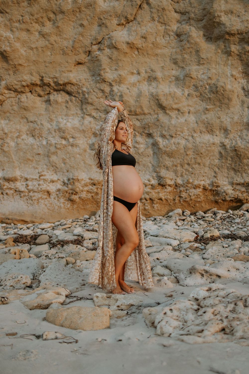 Expecting mum posing against the cliff face during a natural sunset pregnancy photography session at Port Willunga, South Australia