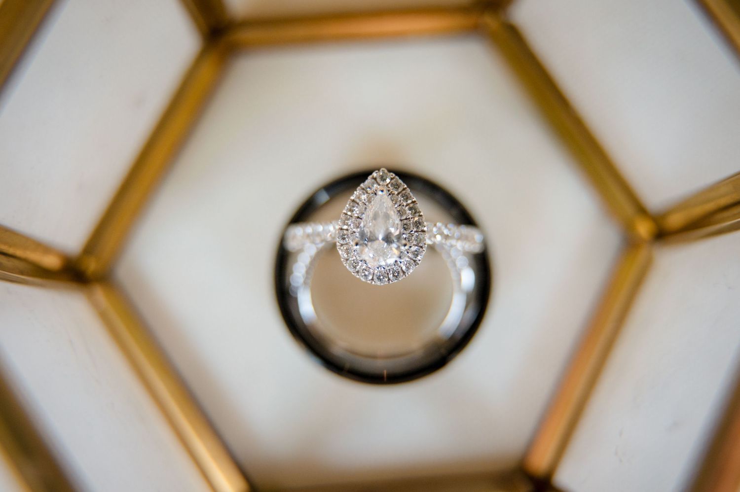 Close-up of a pear-shaped diamond engagement ring in a silver setting nestled in a geometric box.