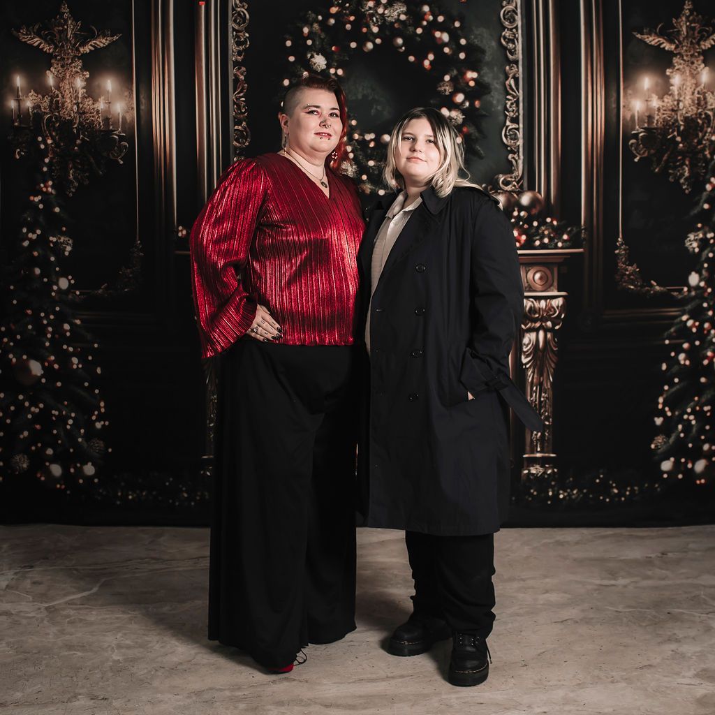 A festive holiday portrait in front of a decorated backdrop with twinkling lights and garland.  Image by Veronica Mai Dominguez