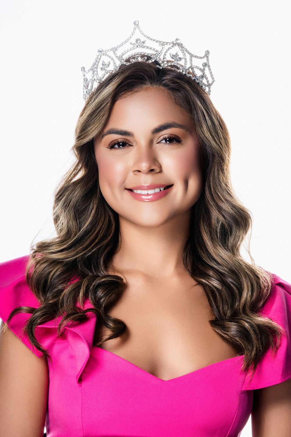 Glamour portrait with crown and bright pink dress against white background.