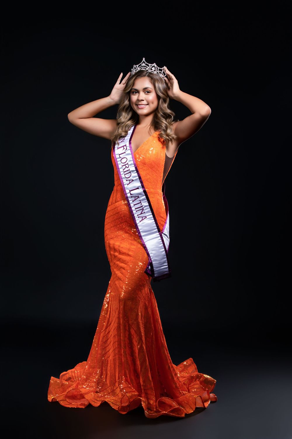 Dynamic poses in a bright orange sequined gown with pageant sash and crown.