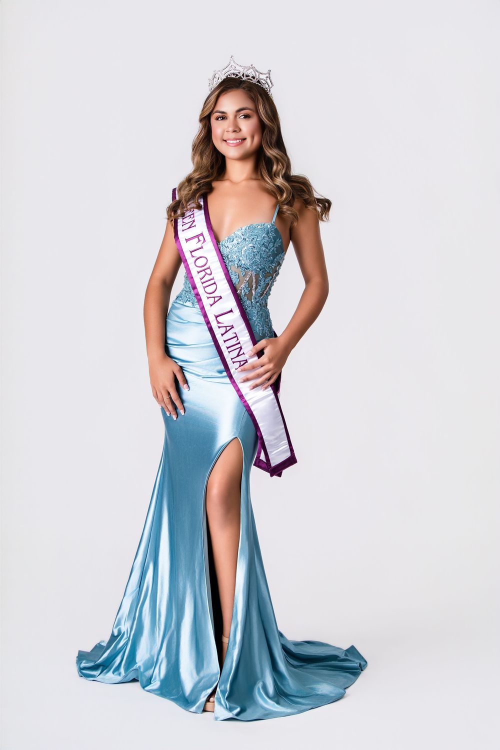 Pageant photoshoot featuring light blue satin gown with high slit and crown.