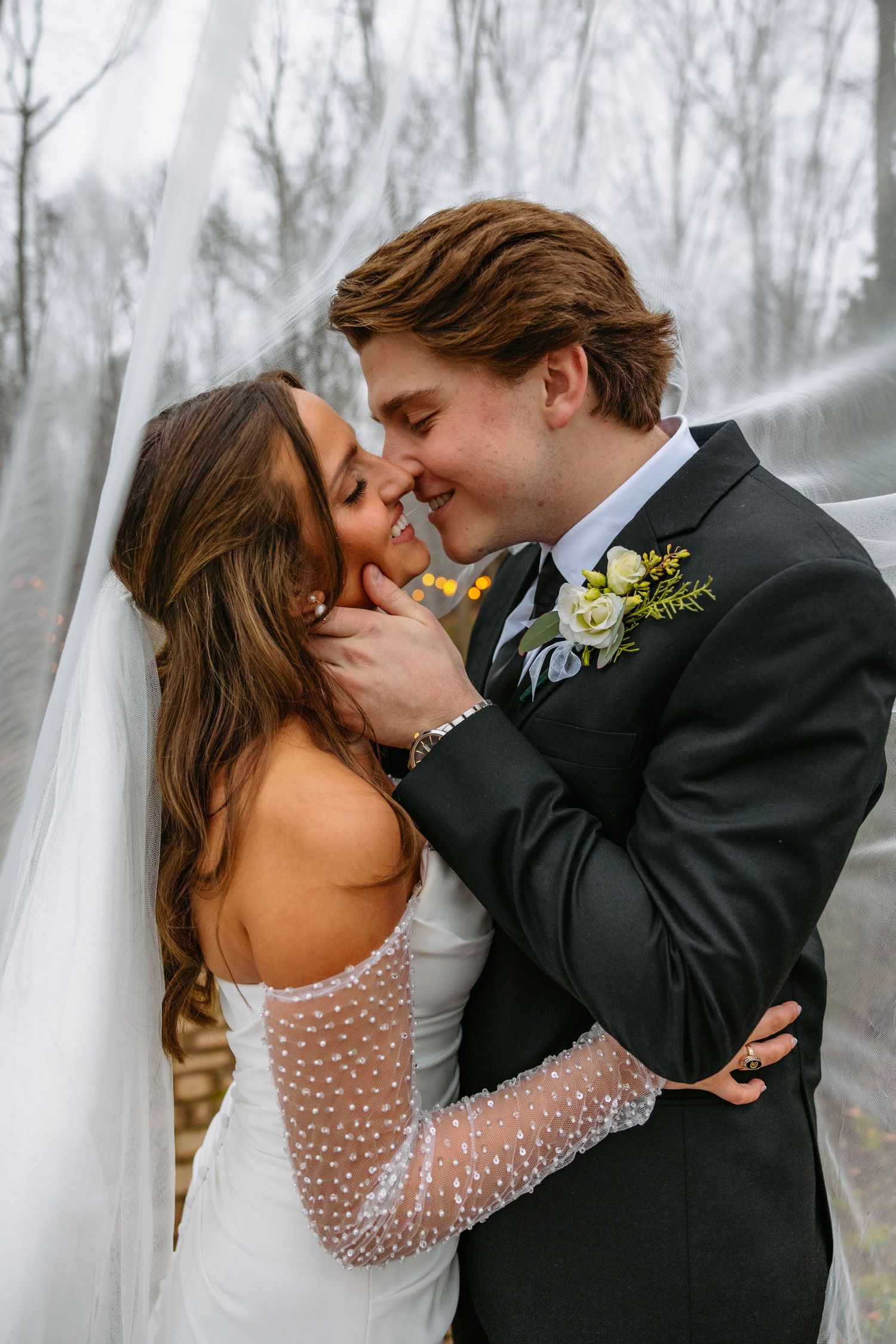 Romantic wedding portrait showing a tender moment between newlyweds in a misty forest setting.
