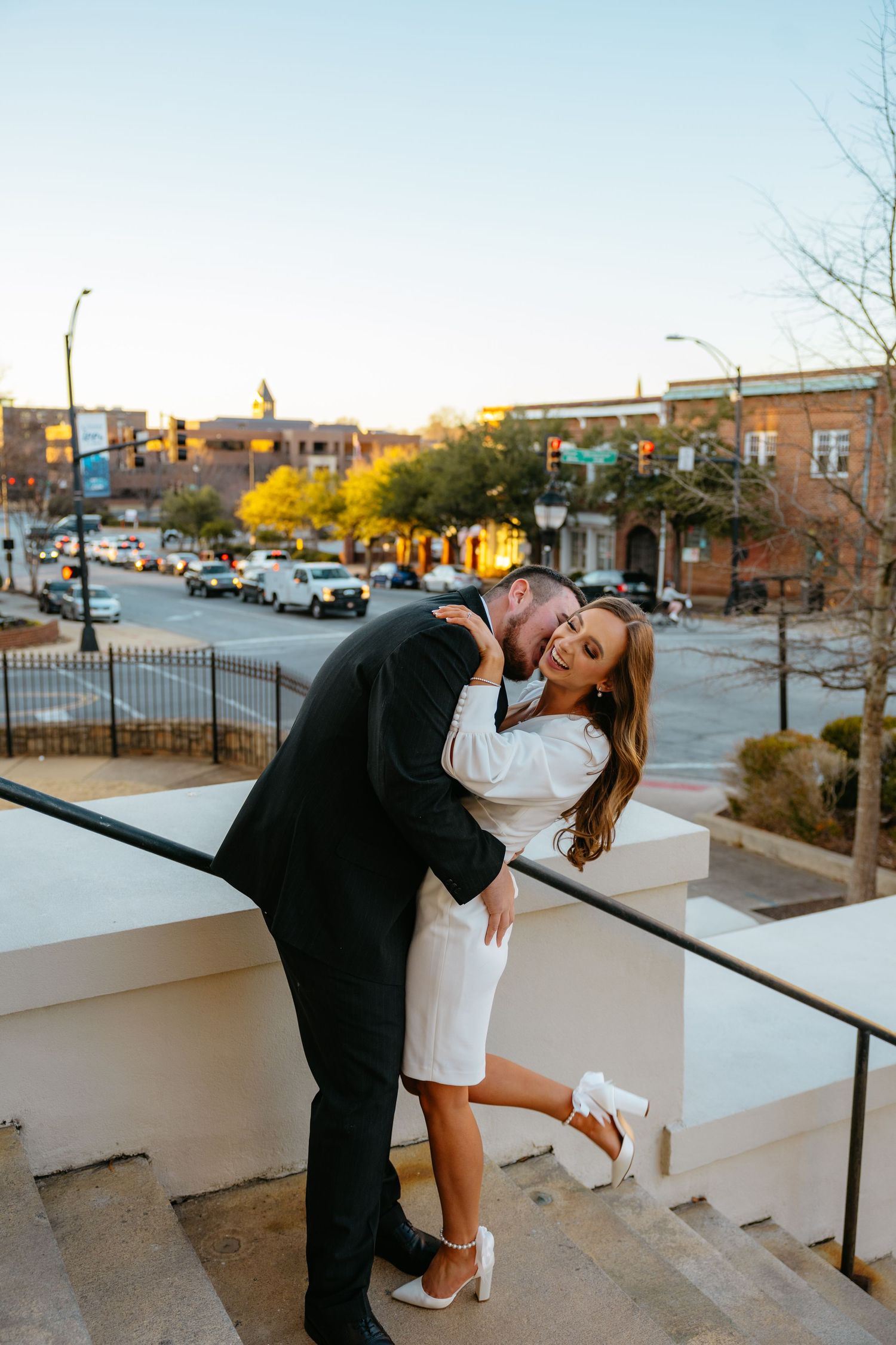 Romantic dip pose on urban rooftop during sunset engagement session.