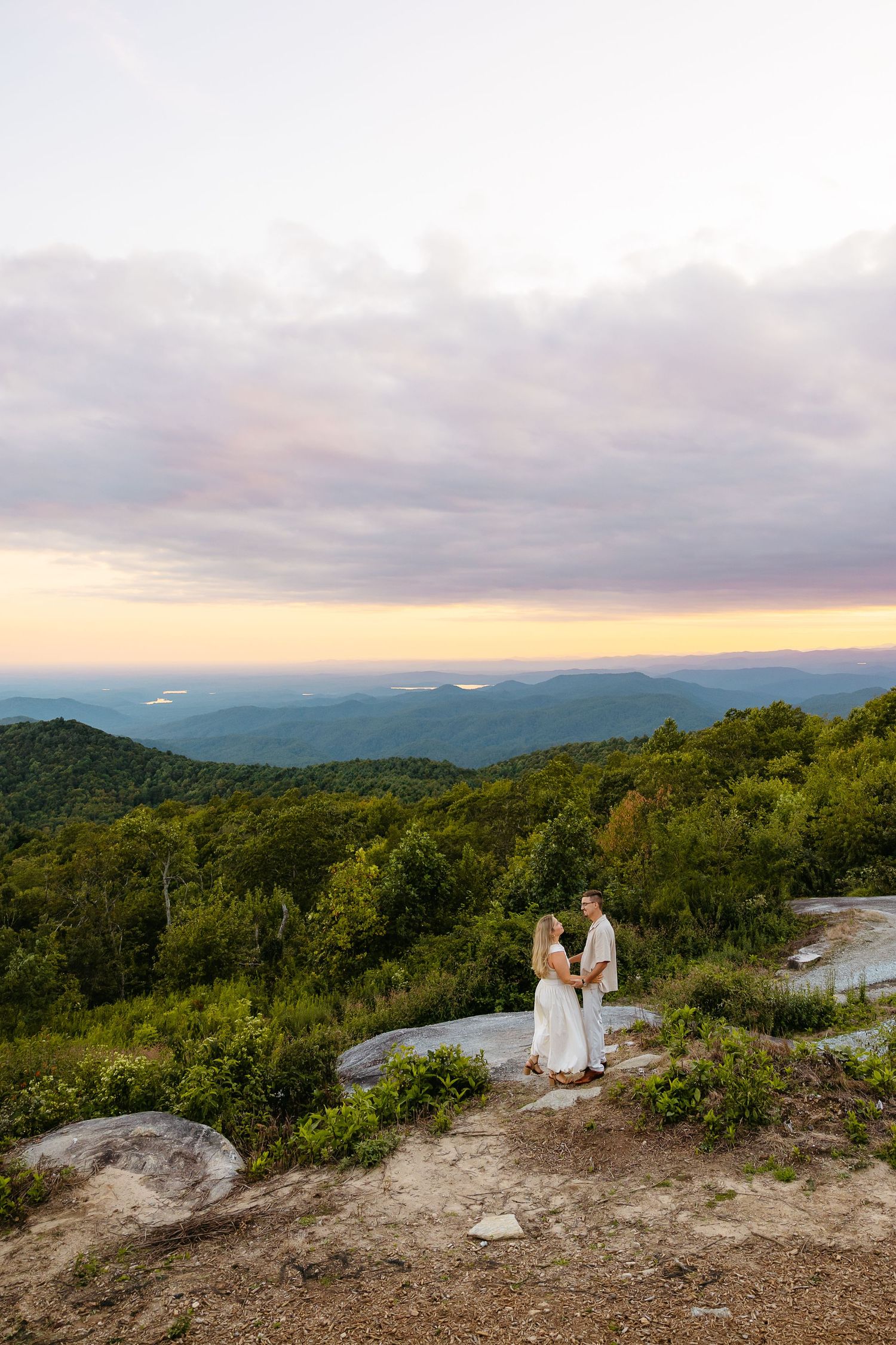 A stunning mountaintop wedding ceremony with a backdrop of rolling mountains and sunset skies over the Blue Ridge Mountains.