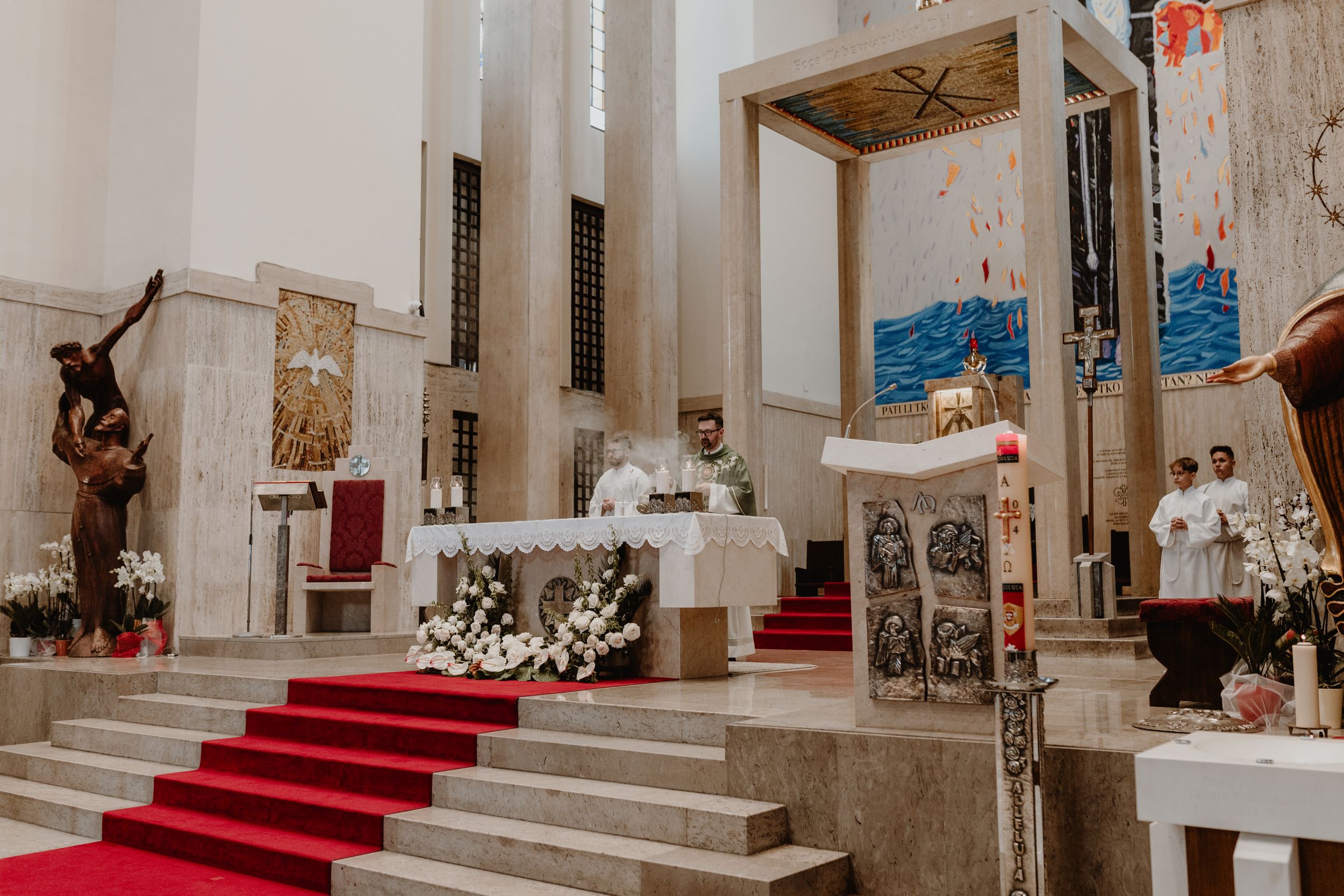 Wide-angle shot of the priest delivering a sermon during the christening ceremony,framed by the church’s ornate interior