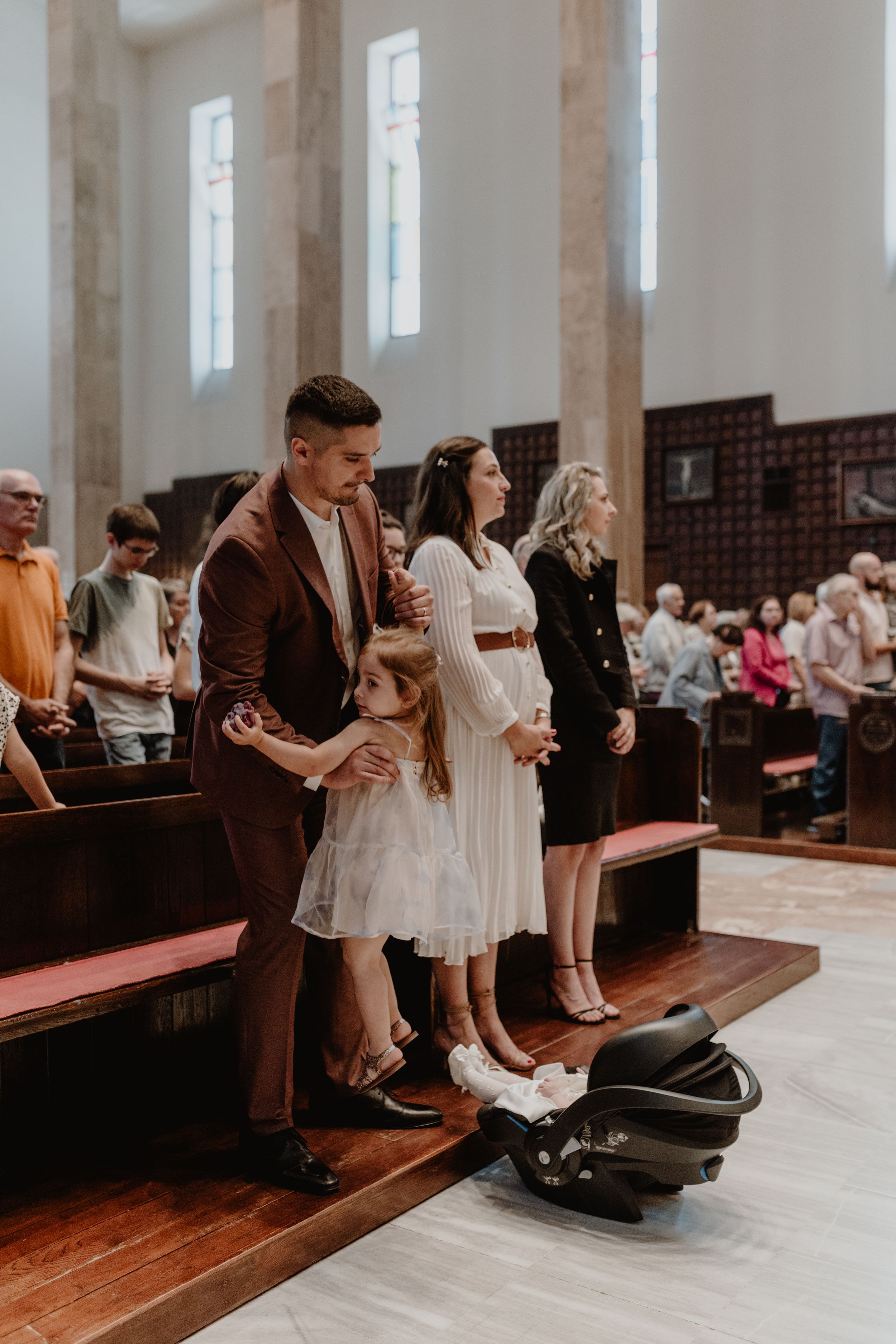 Family in the front row during the christening ceremony, attentively listening to the priest's sermon.