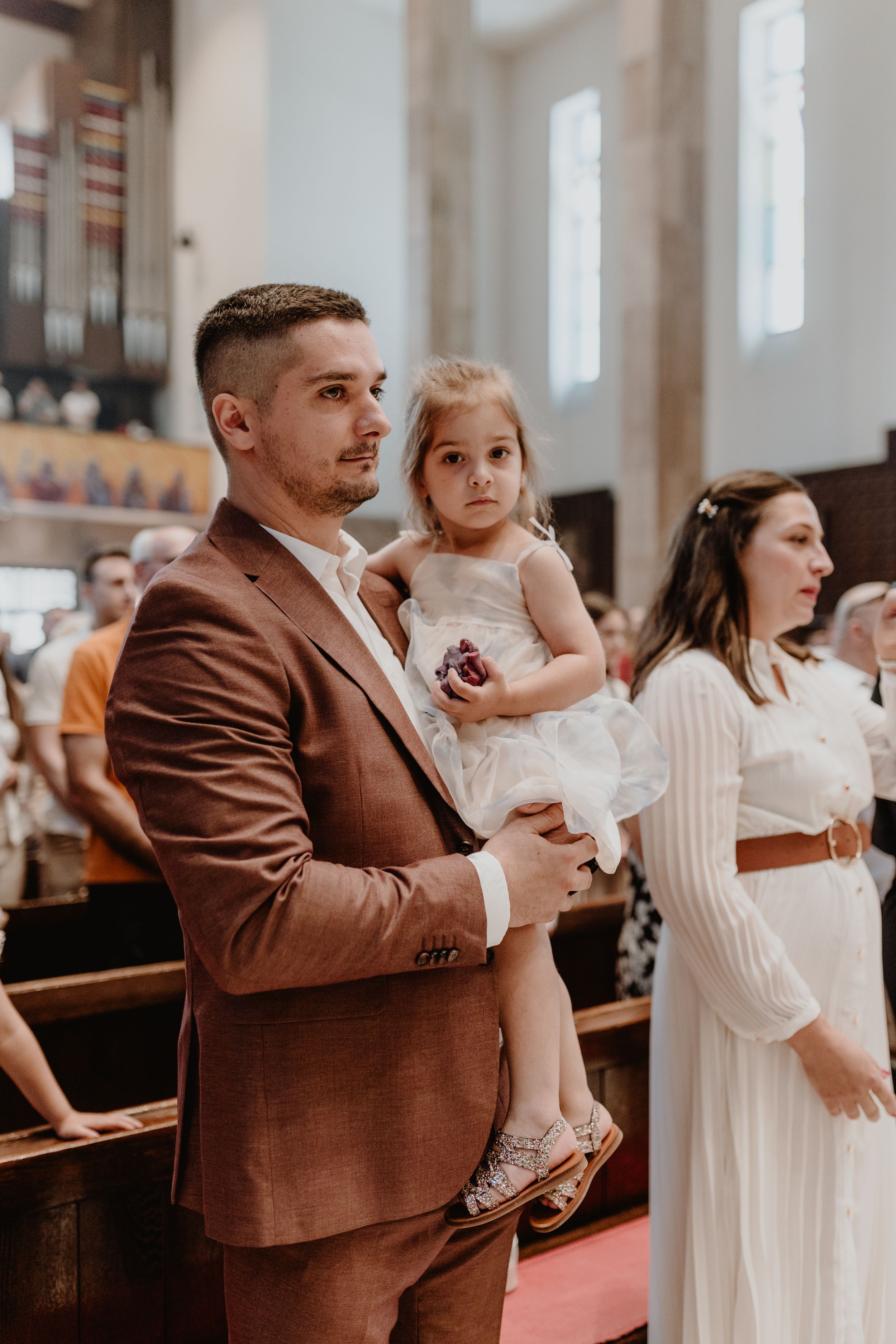 Proud father gently holding his older daughter during the intimate christening ceremony.