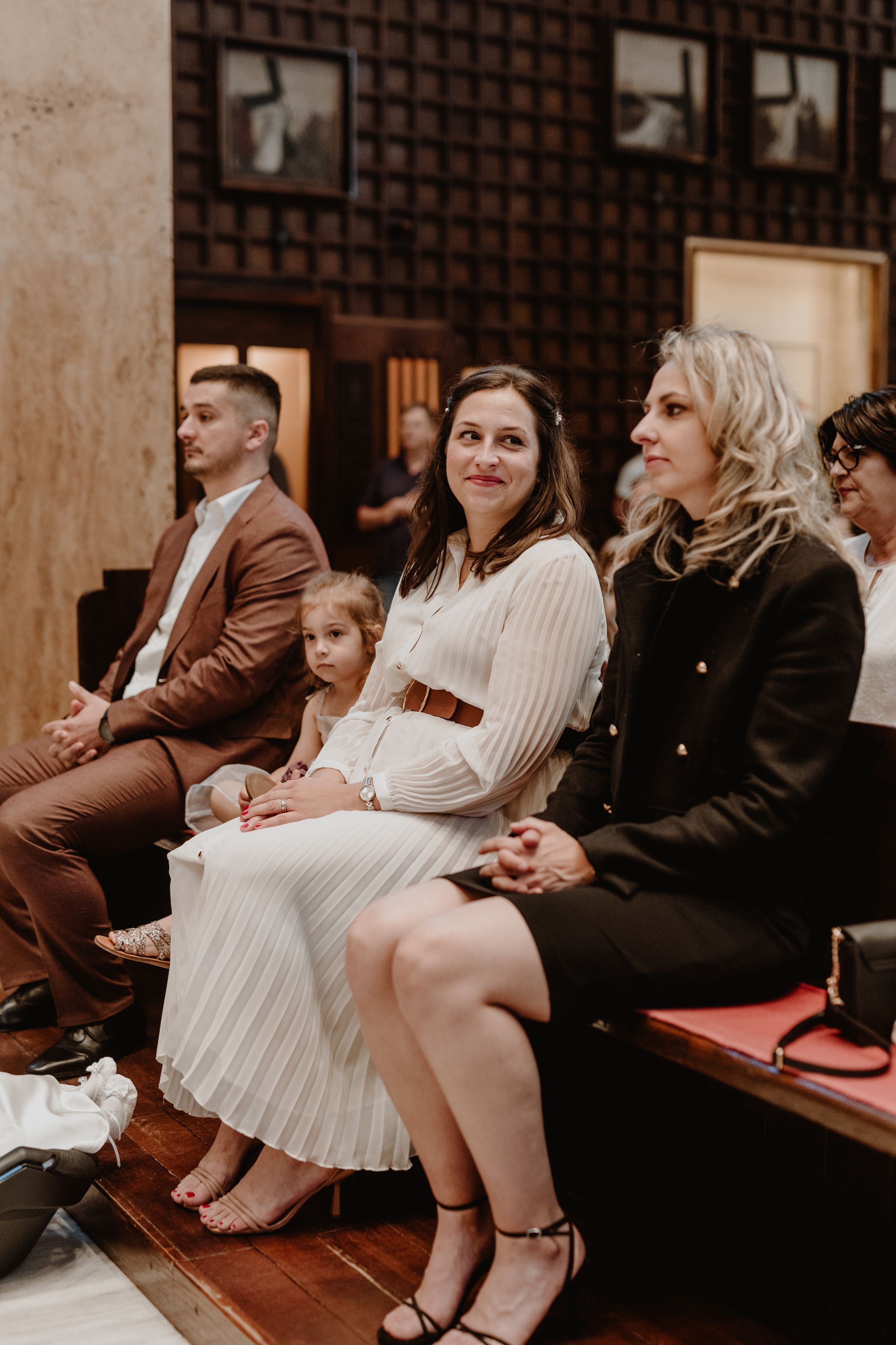 Mom looking over at her daughter's godmother with a warm smile during the christening ceremony.