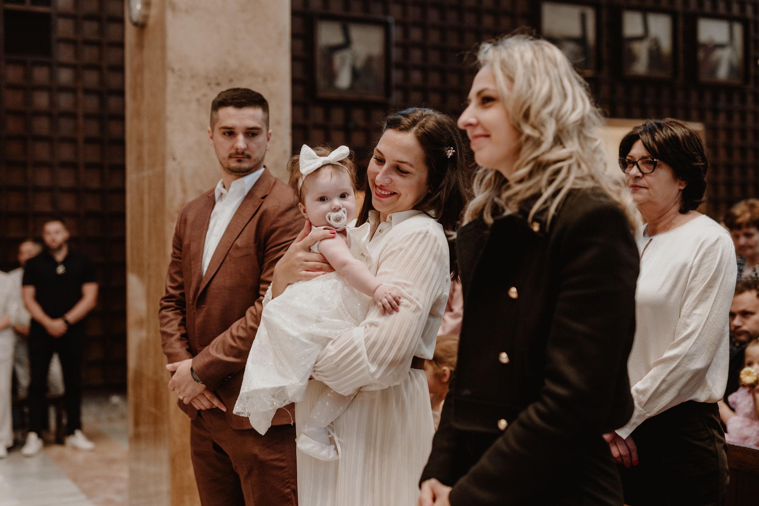 Portrait of mom holding her daughter and smiling warmly during the christening ceremony.