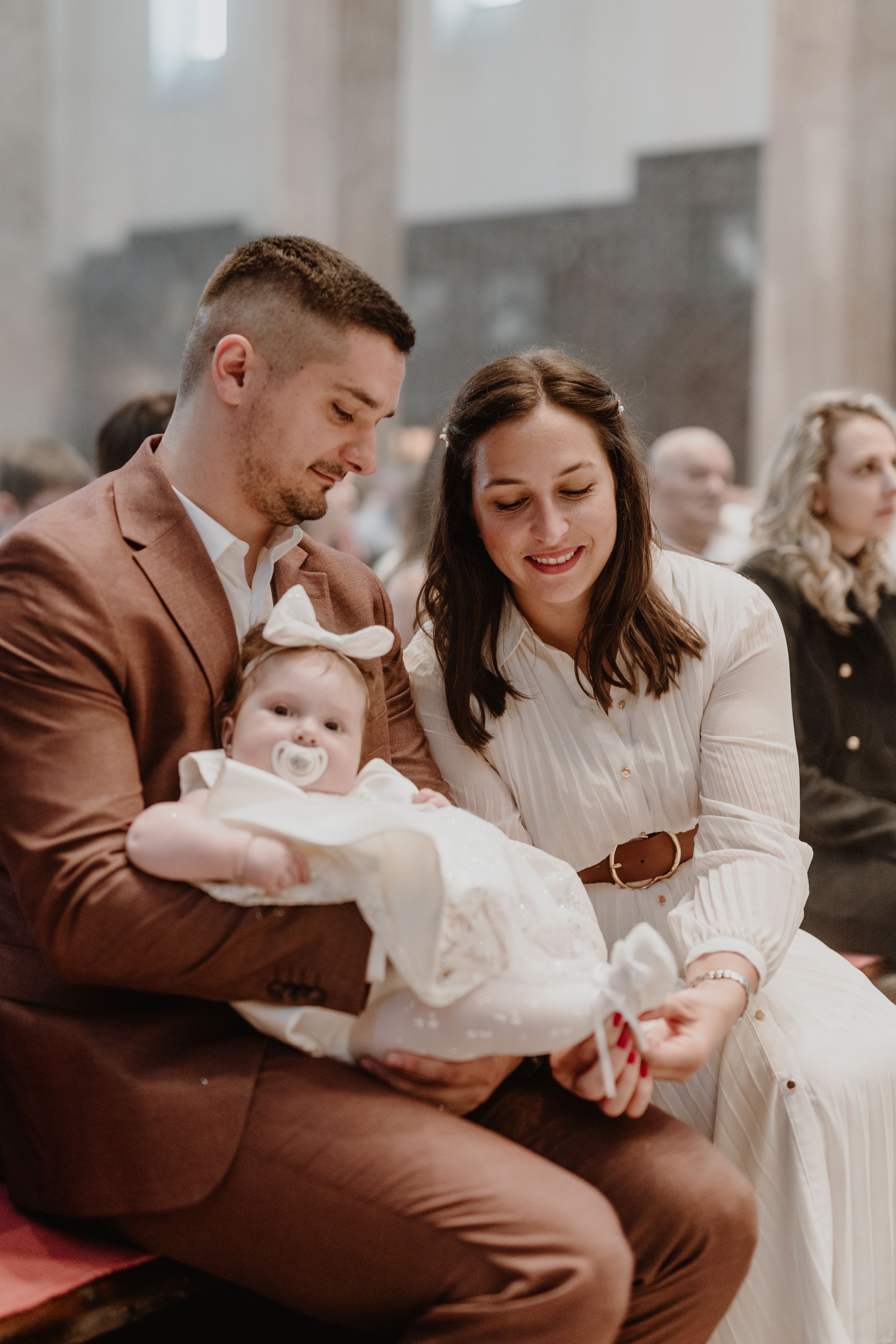 portrait of the father holding the child lovingly, while the mother gently puts on a tiny shoe.