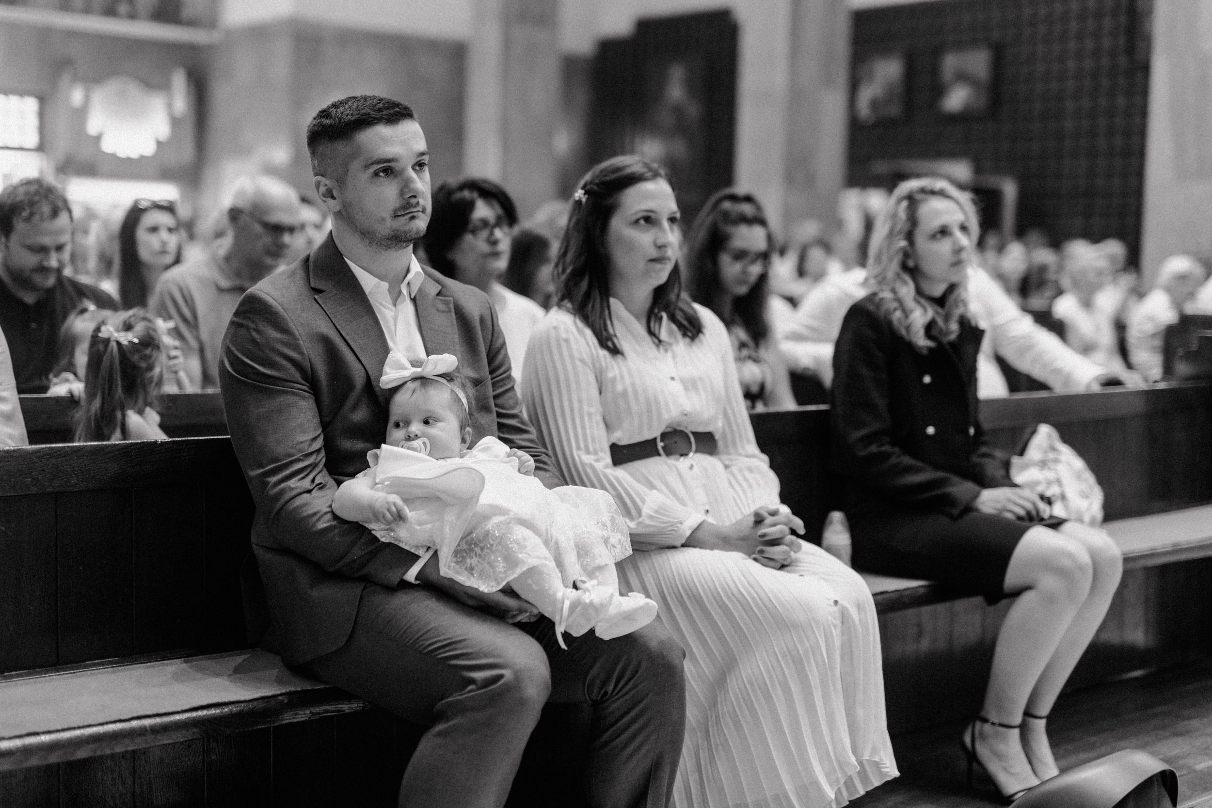 Family sitting in the front row, attentively listening to the sermon during the christening ceremony.