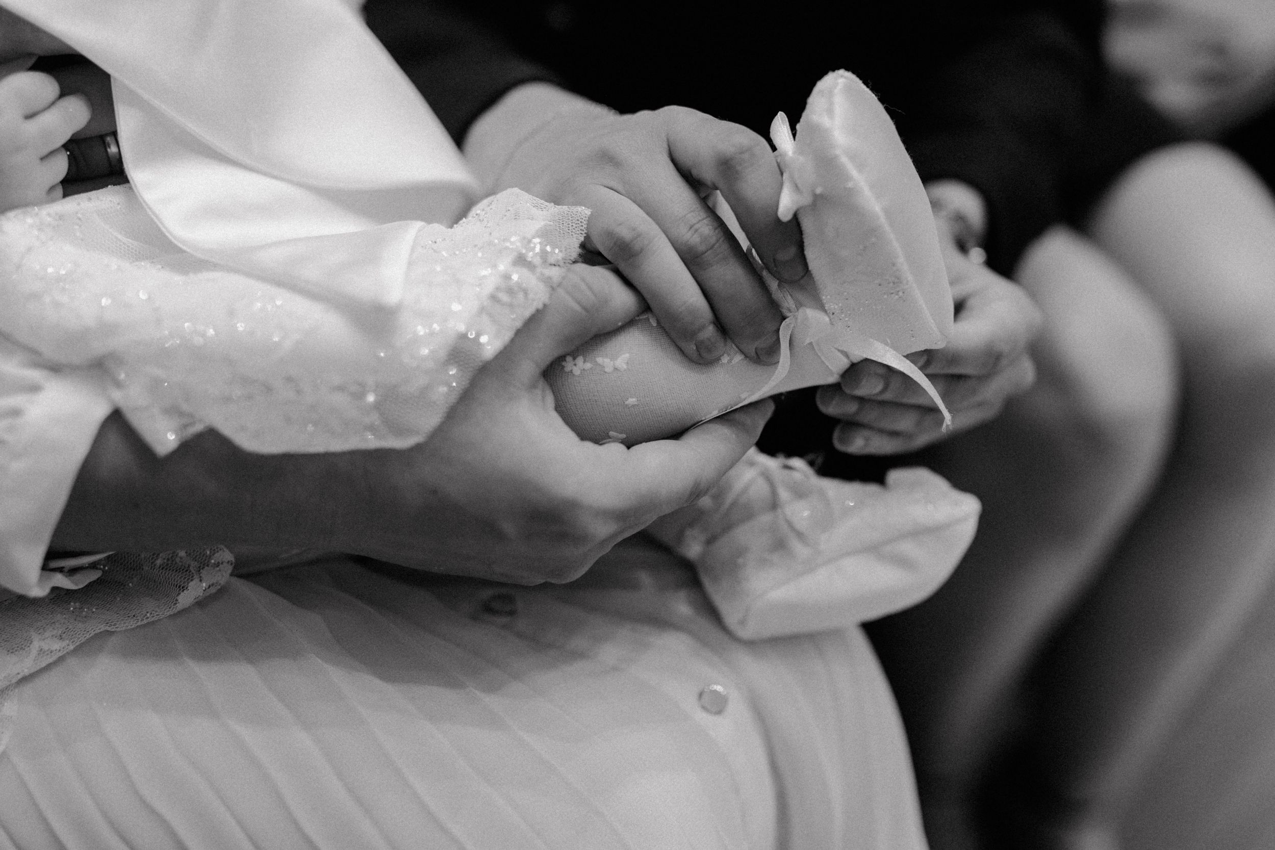 Close up black and white photo of clasped hands with lace details.