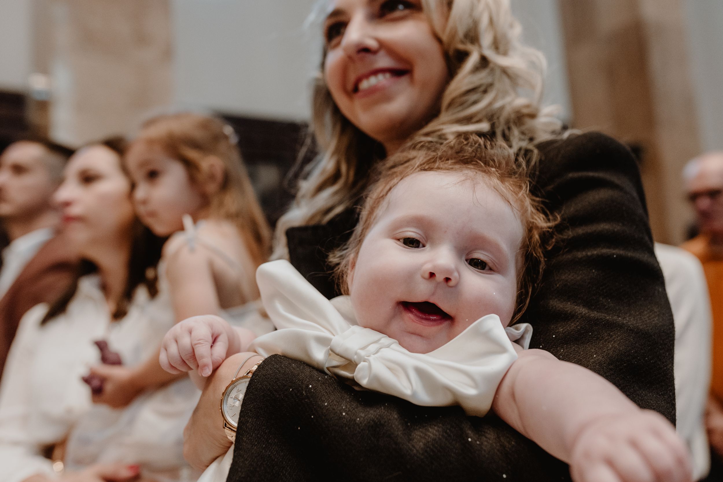 Close-up of the baby's face as the godmother holds her and smiles, capturing a tender and joyful moment in church.