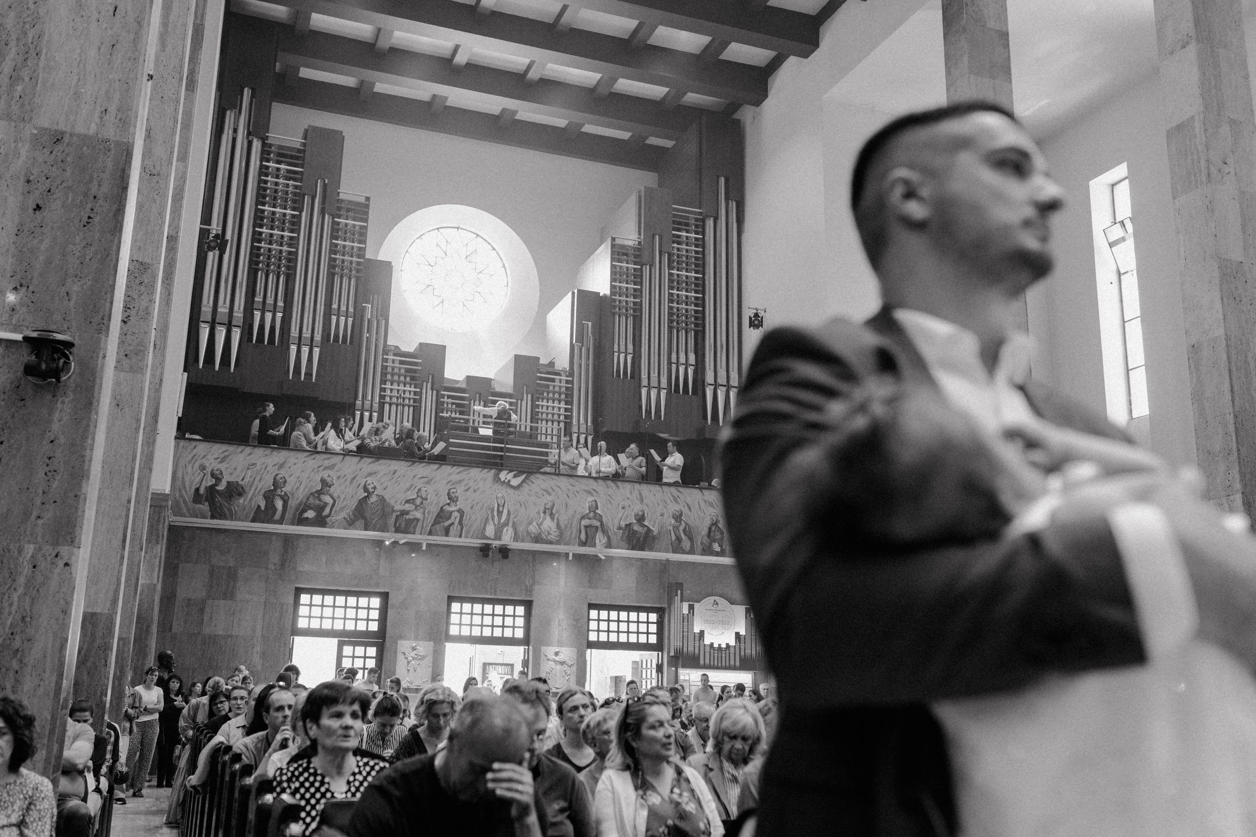 Father holding the baby out of focus in the foreground, with the choir singing passionately in the background in church.
