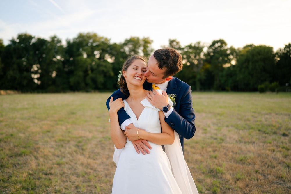A couple embraces in a golden field during sunset creating a romantic outdoor moment.