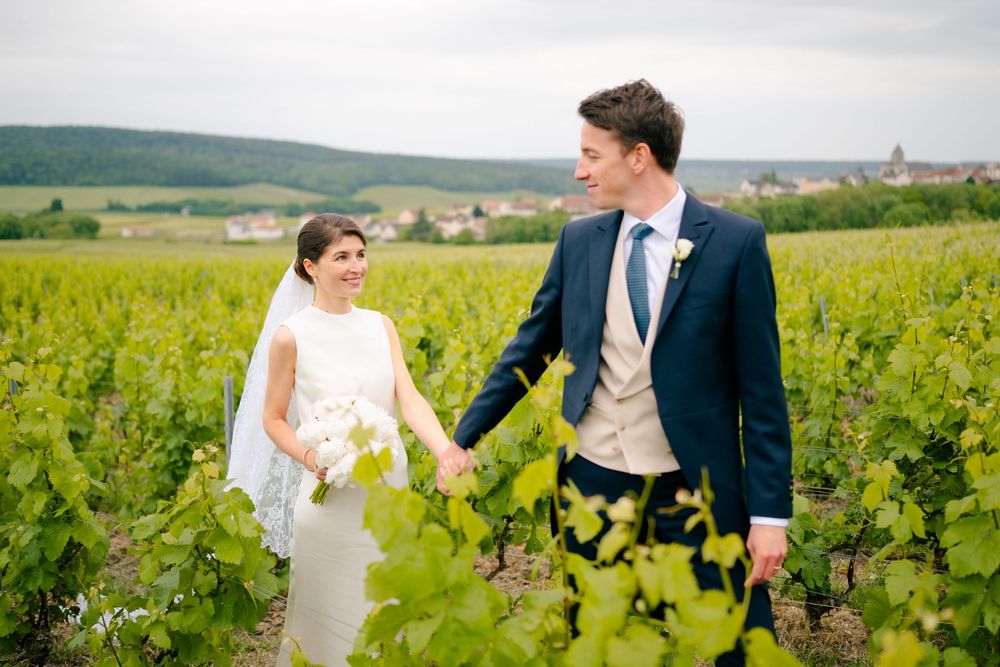 Happy couple walks and laughs together through beautiful vineyard rows in the French countryside.
