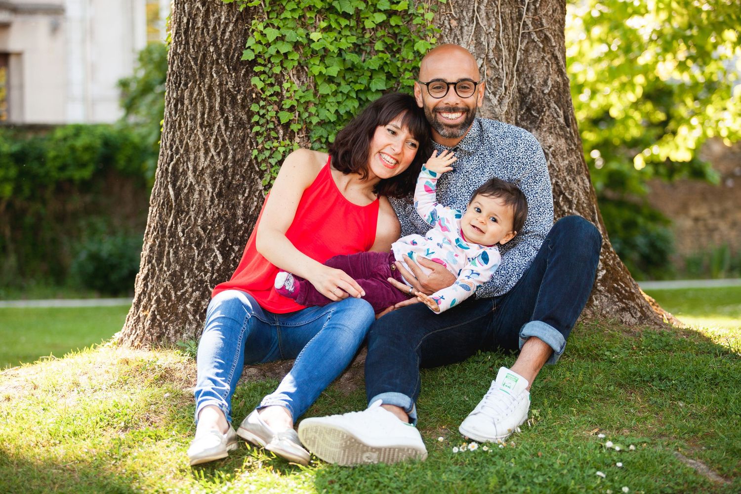 Une famille heureuse appuyée qui pose contre un arbre du Jardin des Plantes de Grenoble