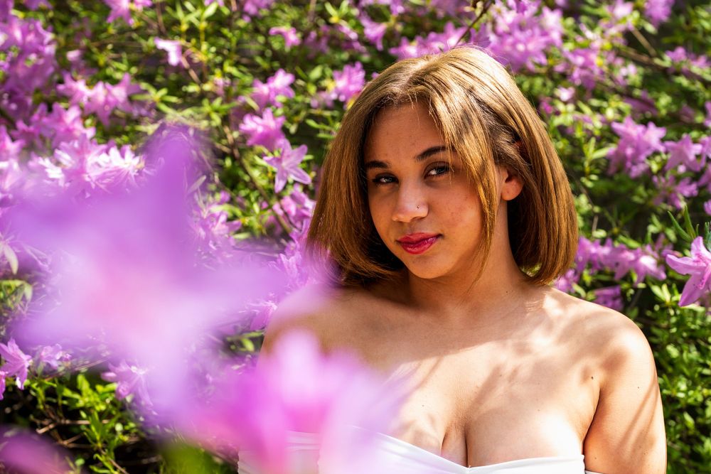 A portrait with vibrant pink flowers framing the scene in a garden setting.
