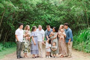 Extended family gathering outdoors on a green wooded path wearing coordinated casual attire. Oahu Family Photographer
