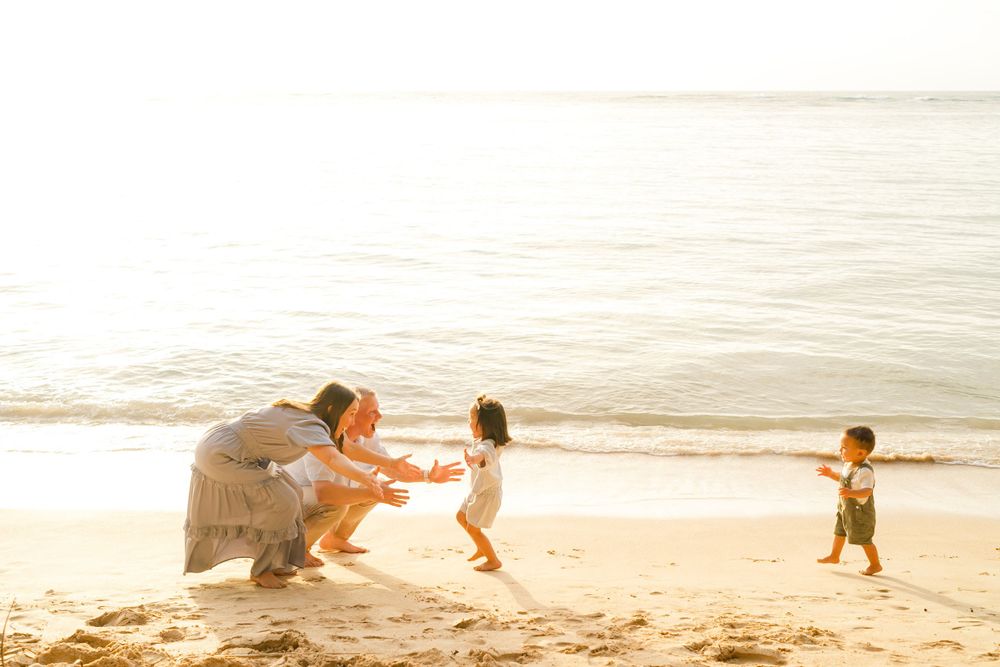 Family playing together on a sun-drenched beach at golden hour. Oahu Family Photographer