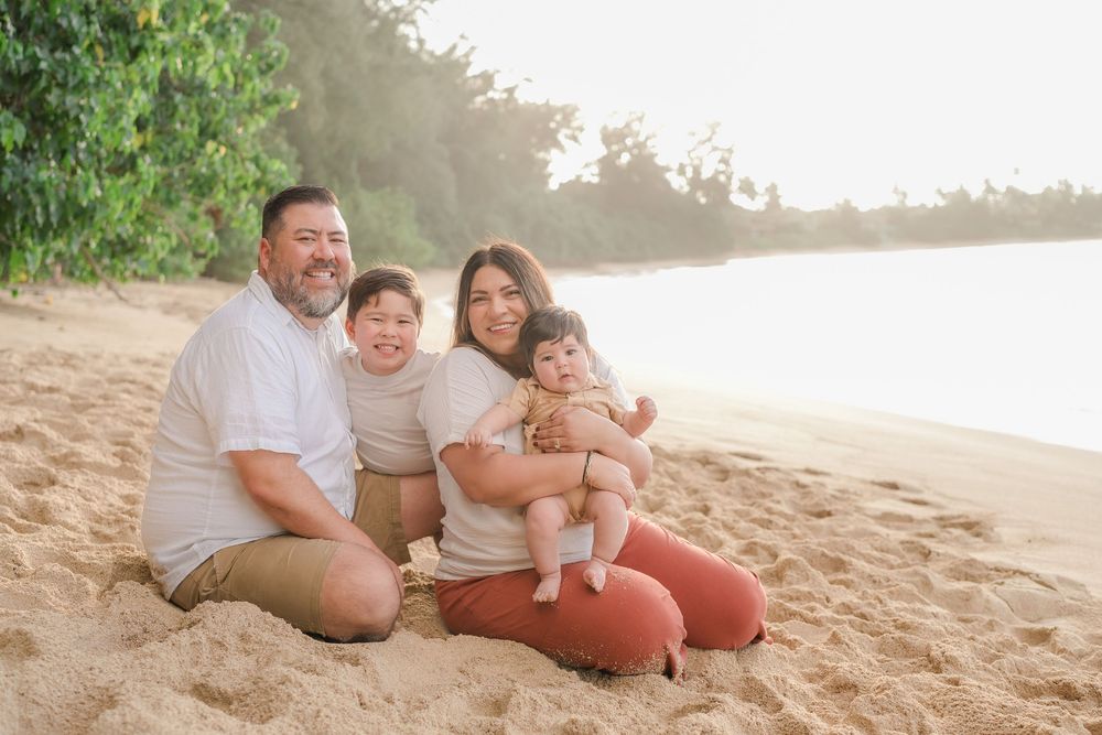 Family enjoying quality time together on a sandy tropical beach at sunset.
