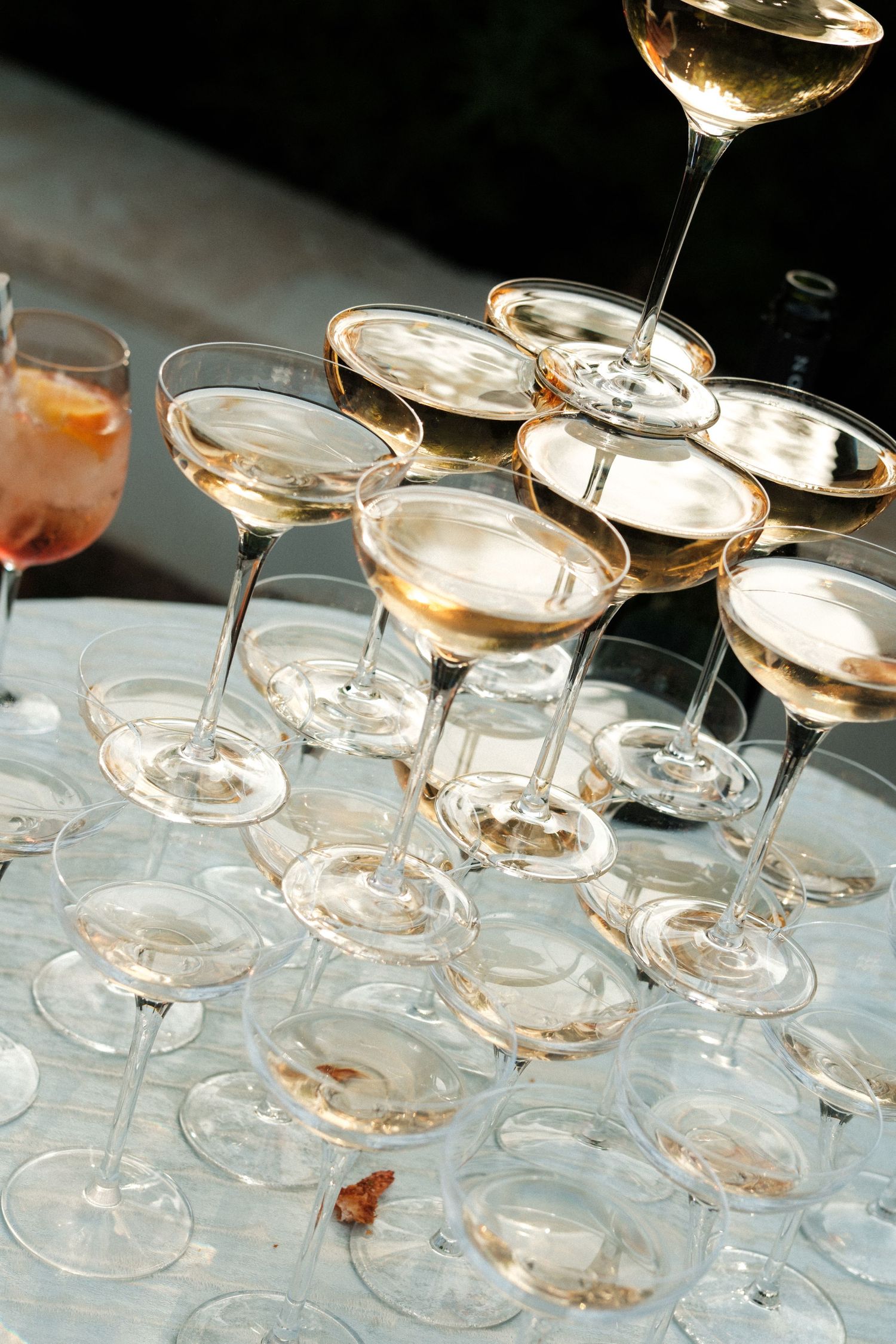 Stacked champagne coupe glasses creating a pyramid formation on reflective surface.