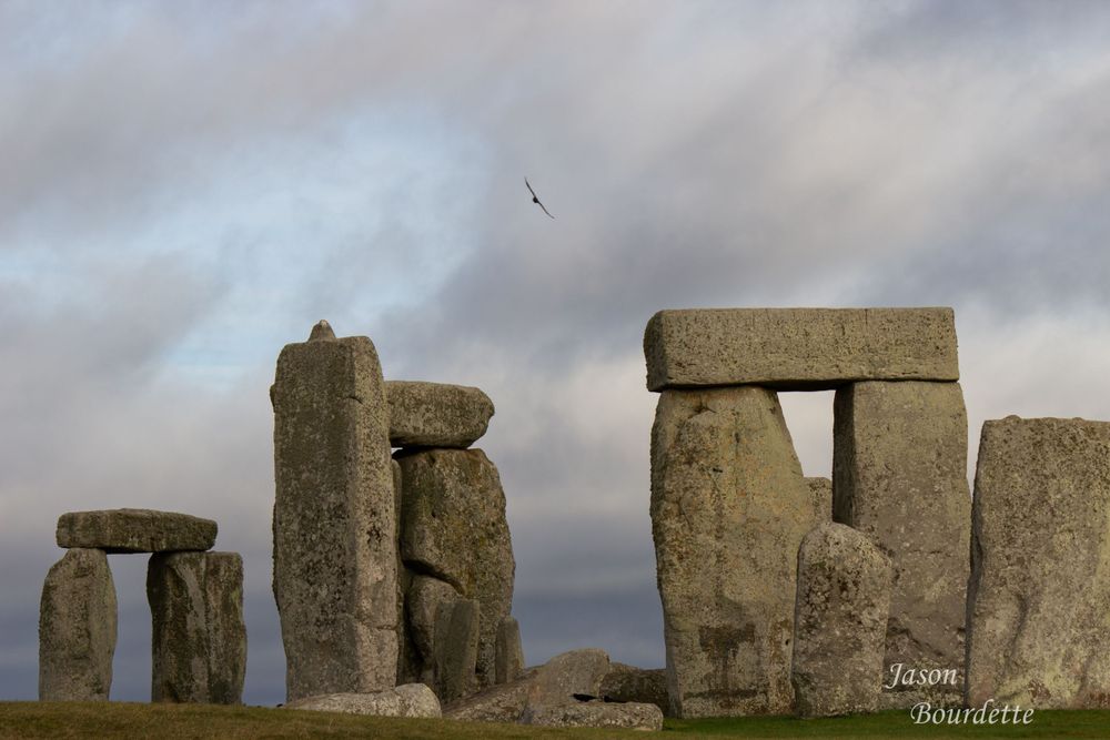 Ancient Stonehenge columns standing tall against a cloudy sky, showcasing their weathered stones and mysterious formation