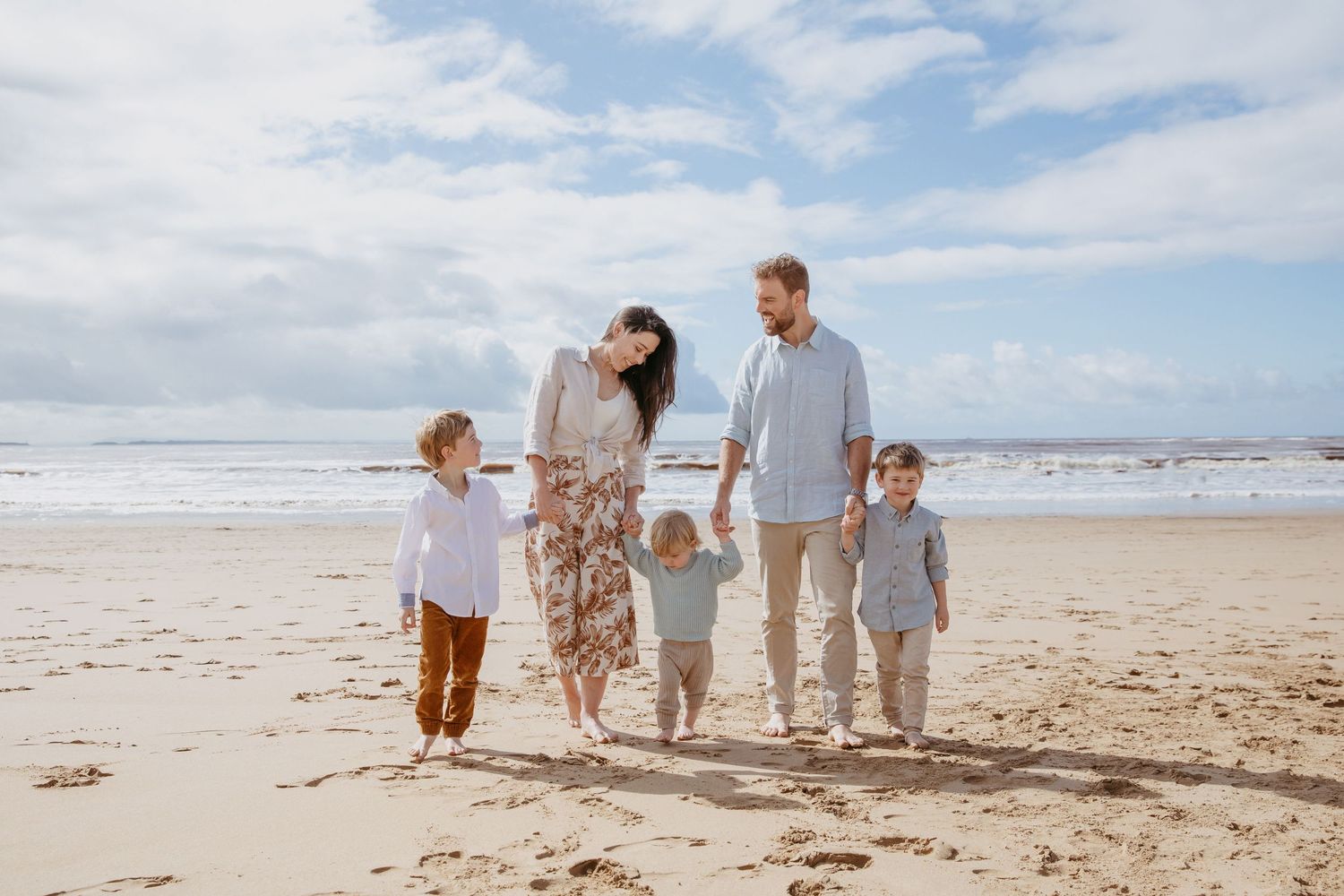 Family holding hands walking along the beach in Ocean Grove