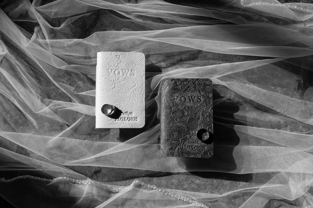 Two wedding vow books laid on sheer fabric in black and white photography.