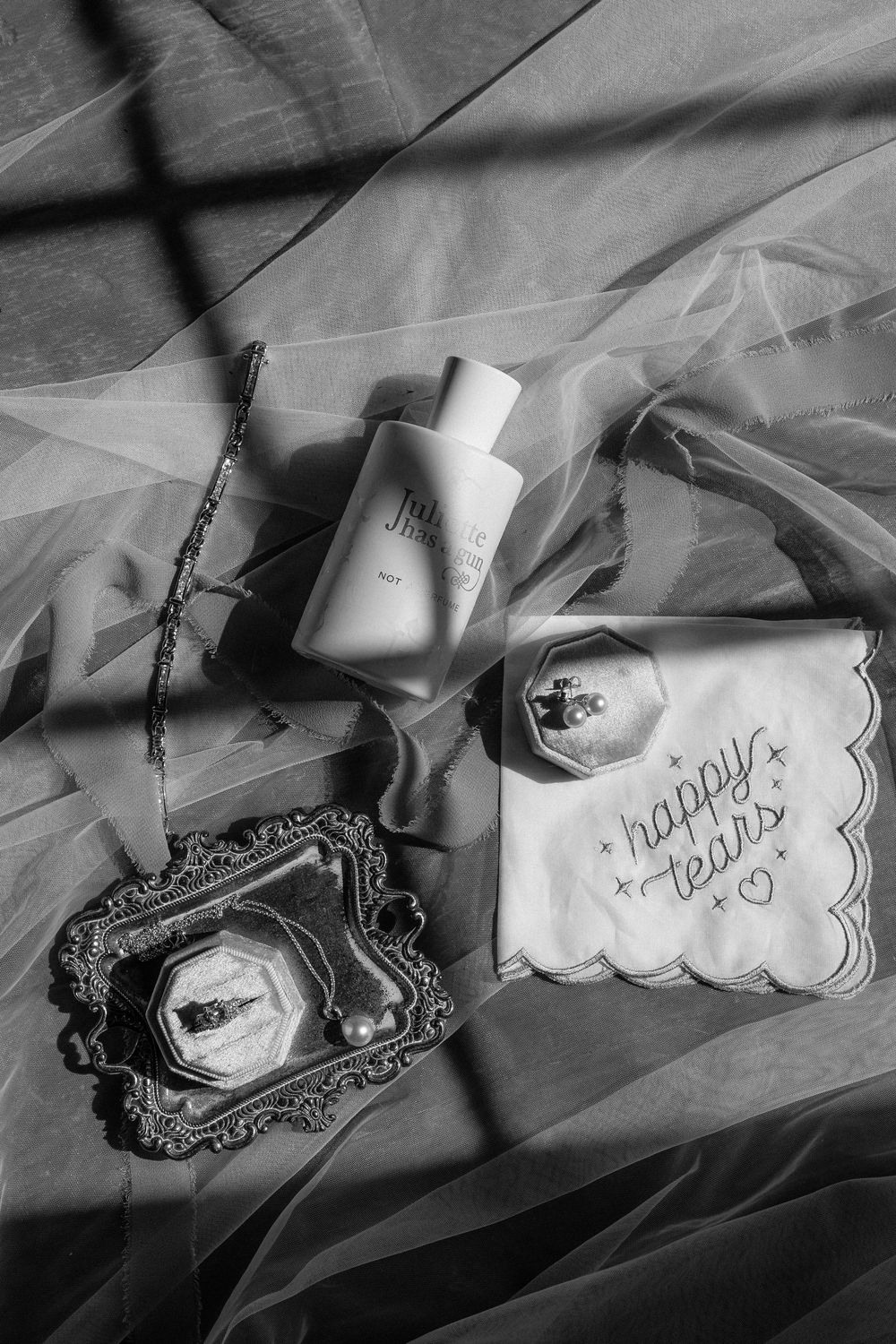 Black and white detail shots of elegant wedding stationery and decorative elements on a textured surface.