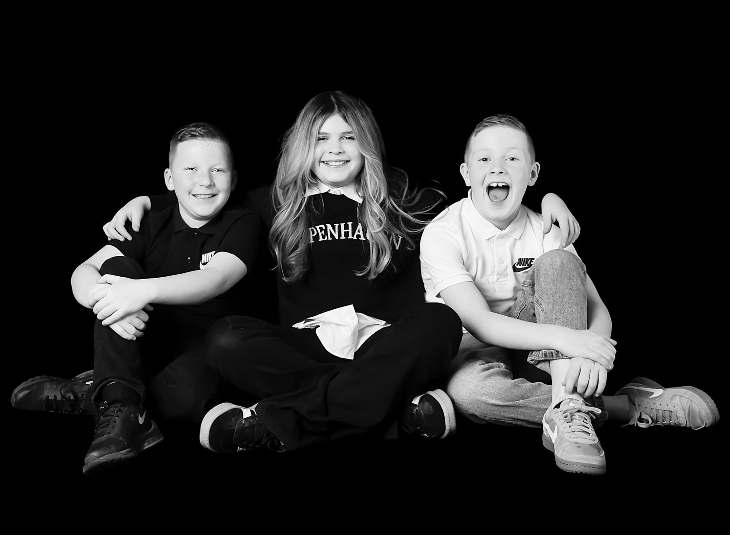 Sister and brother black and white studio photography by Nicola in Woodside, black background portrait capturing timeless sibling connection
