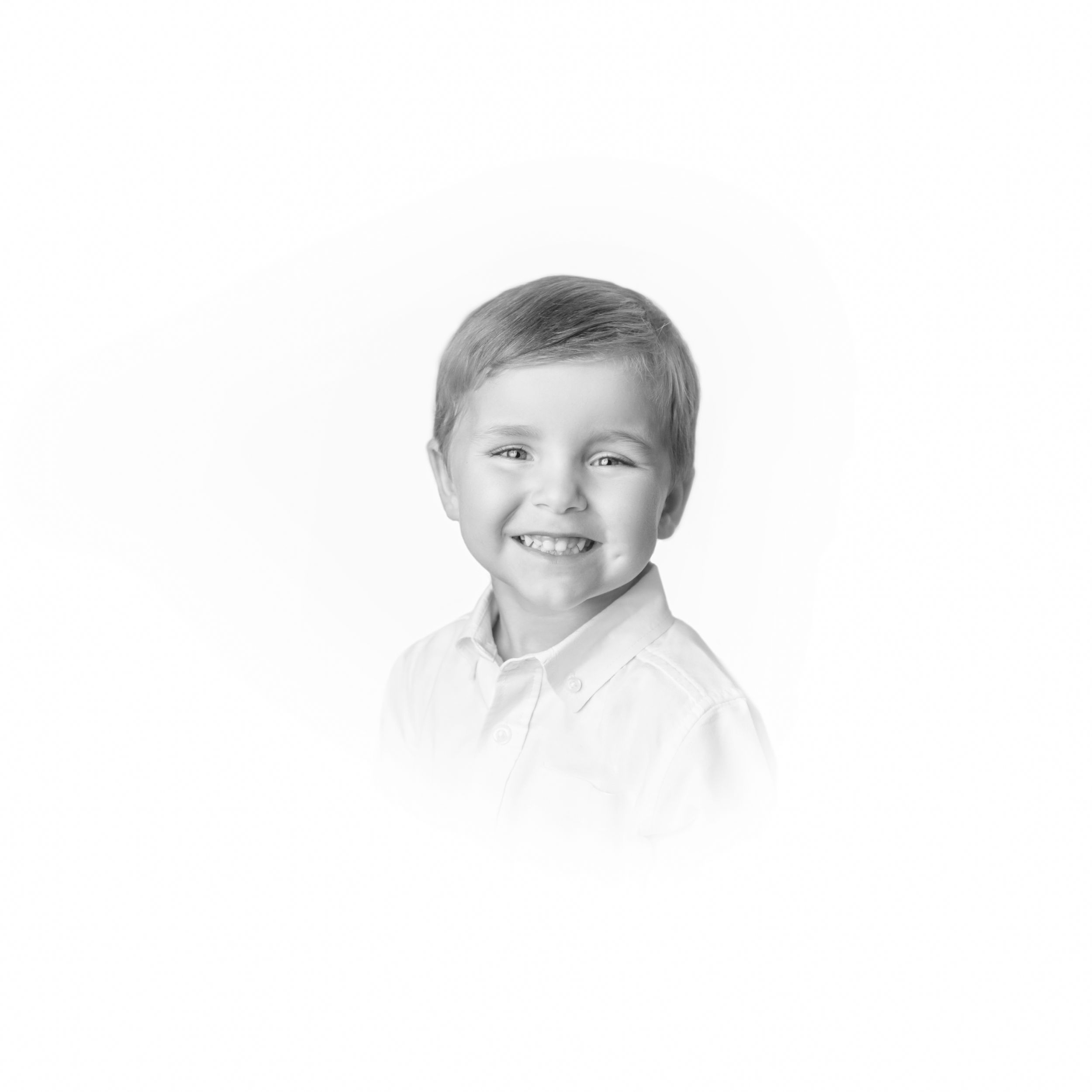 Black and white portrait of smiling child wearing white collared shirt.