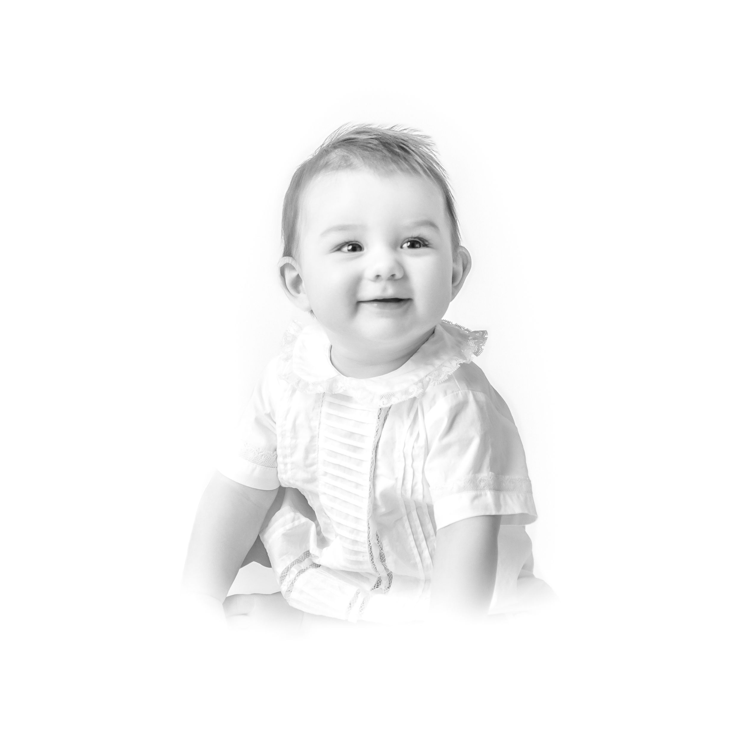 Black and white portrait of baby in white outfit smiling at camera.