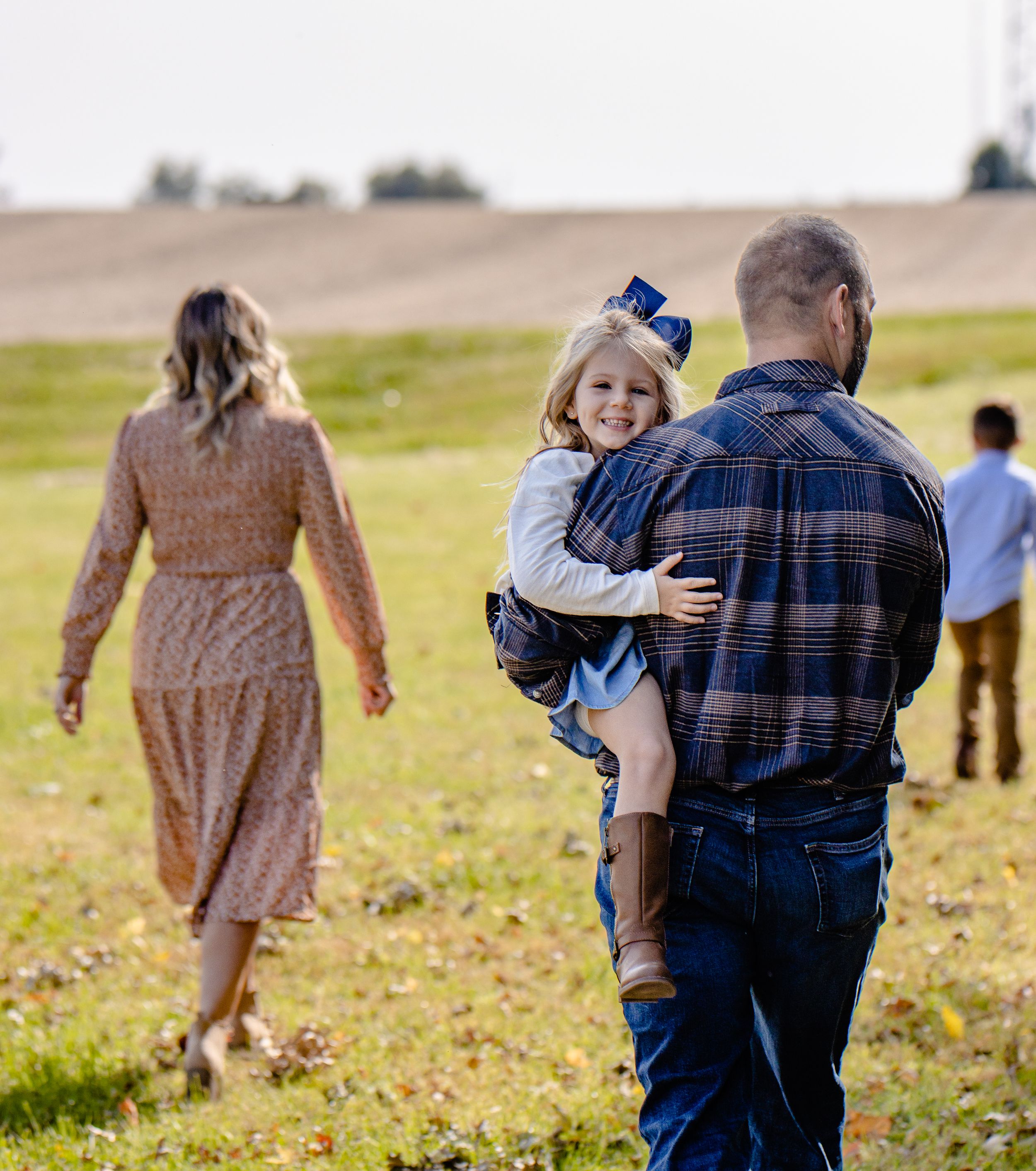A candid family moment in a grassy field with soft golden lighting.