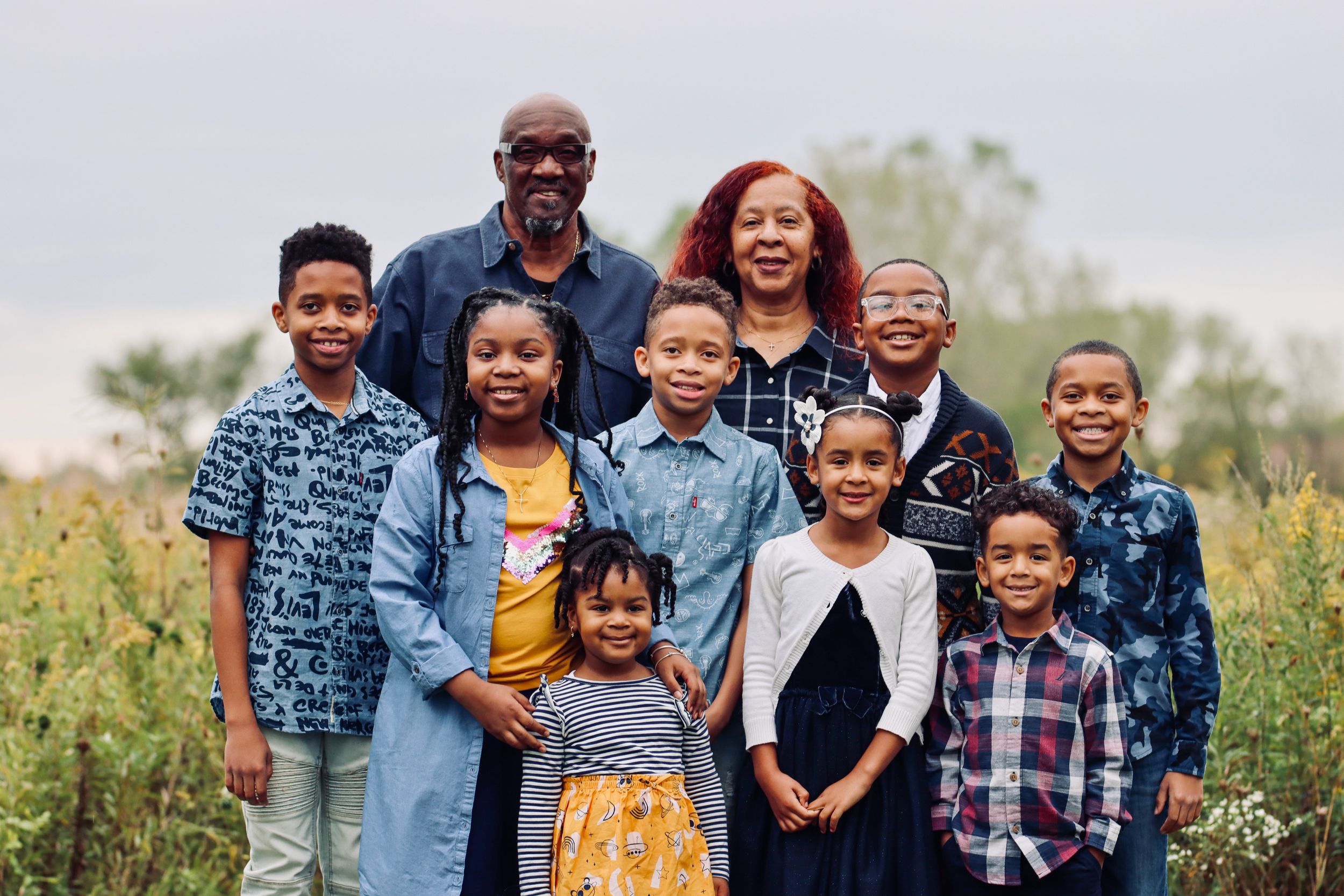 Group portrait of family members posing together in outdoor field setting.