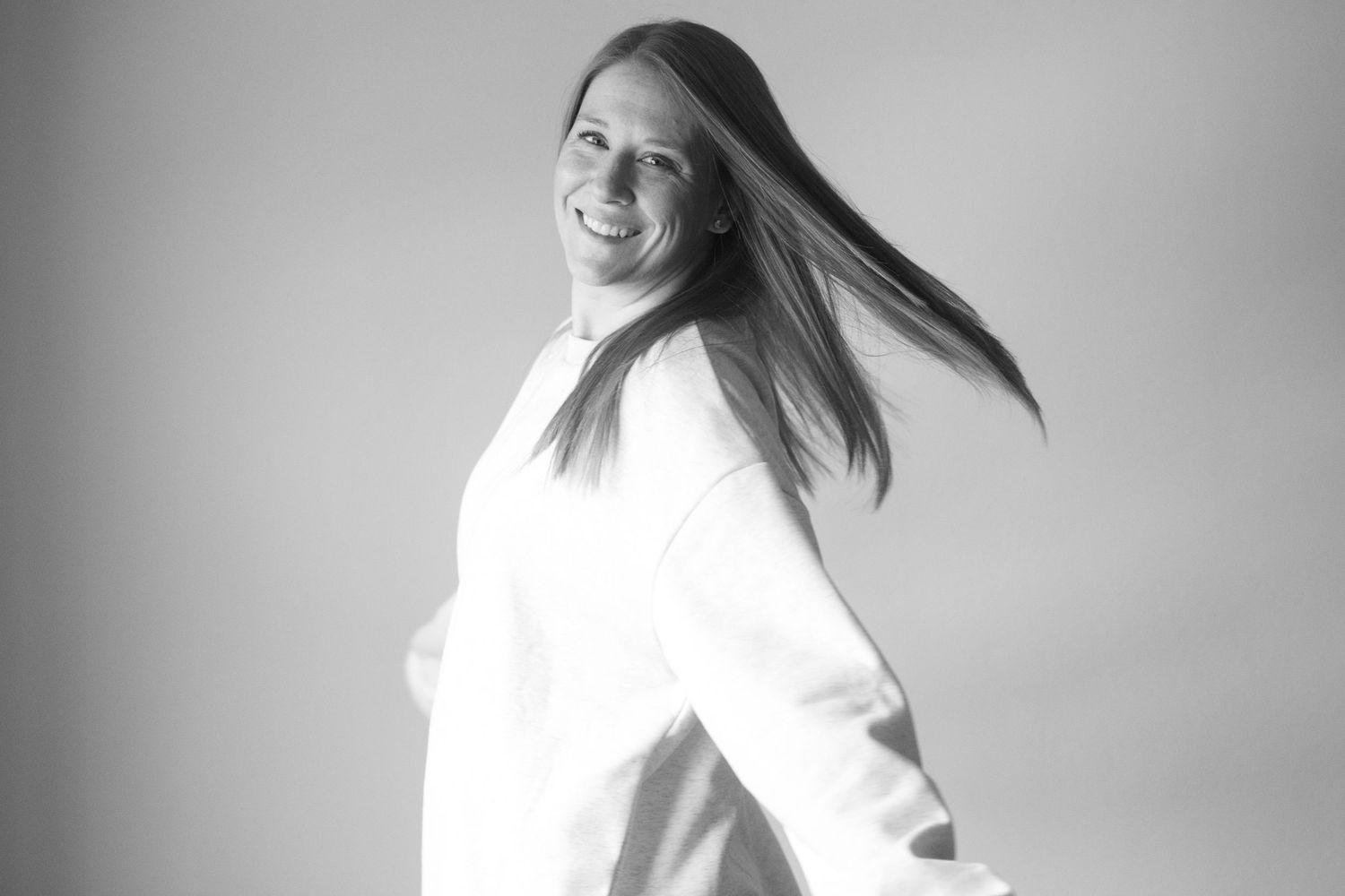Black and white portrait of someone in white with flowing hair in motion.