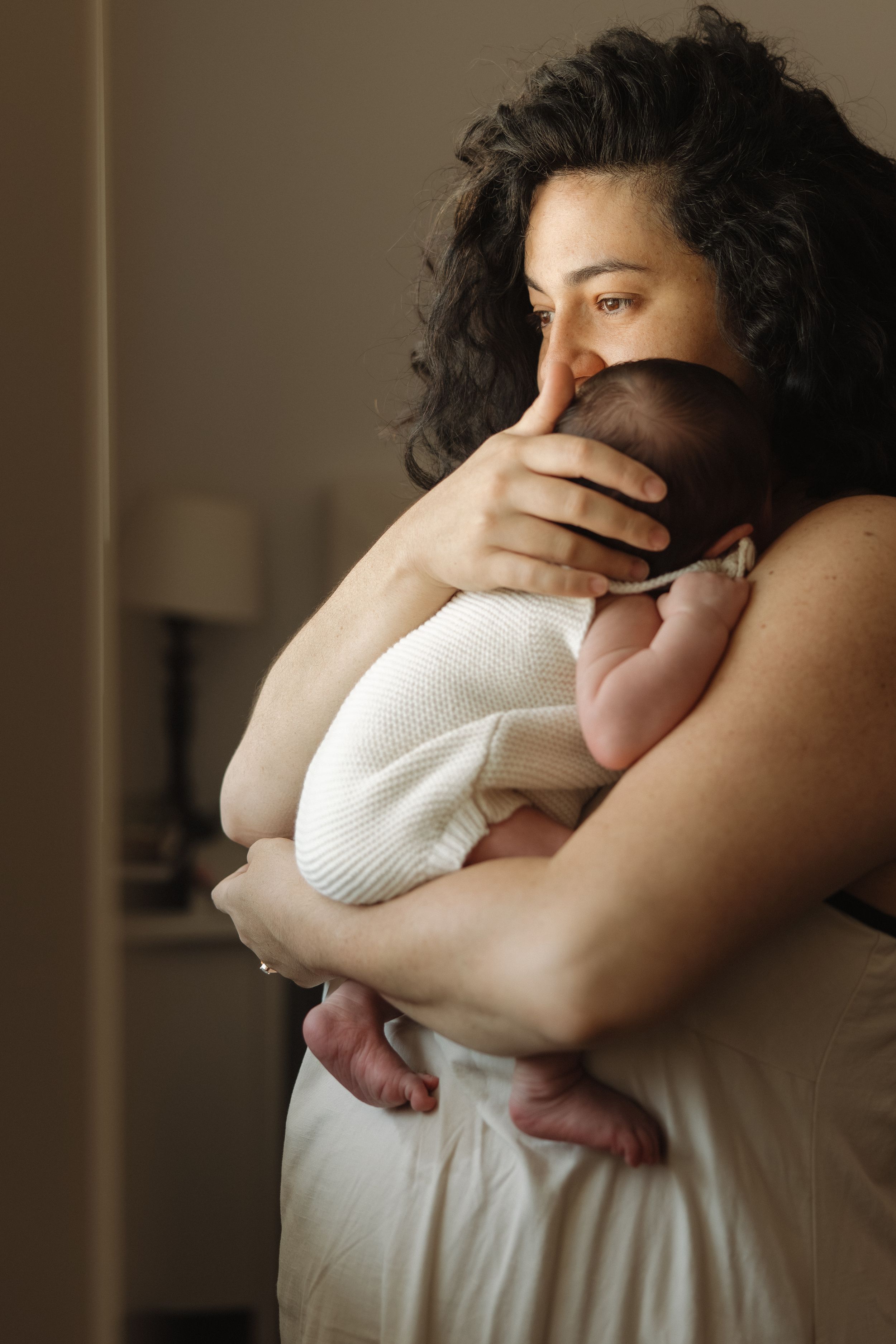 A mother tenderly holds her newborn baby close to her chest, gently cradling the infant in her arms.