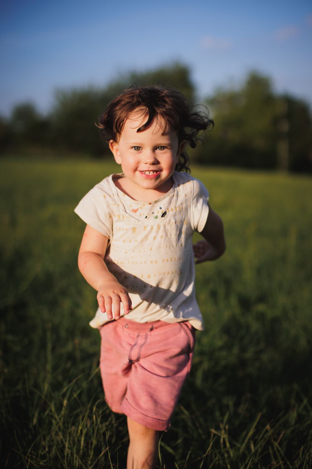 Petite fille qui coure dans un champ en dordogne pendant un shooting famille