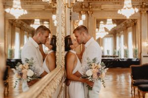 élégant couple romantique s'embrasse dans une salle de bal ornée de lustres en cristal et de murs en miroir de rennes retenant un bouquet