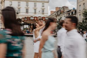 couple qui s'embrasse devant un mouvement flou de personnes passant devant un carrousel vintage sur la place de la ville de rennes