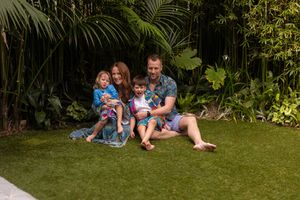 A group of people relaxing together on lush green grass in a garden setting on a sunny day.