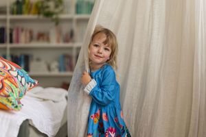 A series of photos showing a young child in a blue dress playing and dancing in a bright interior room.
