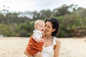 Parent and baby sharing a tender moment on a sandy beach.